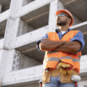 Man in construction uniform standing in front of unfinished building